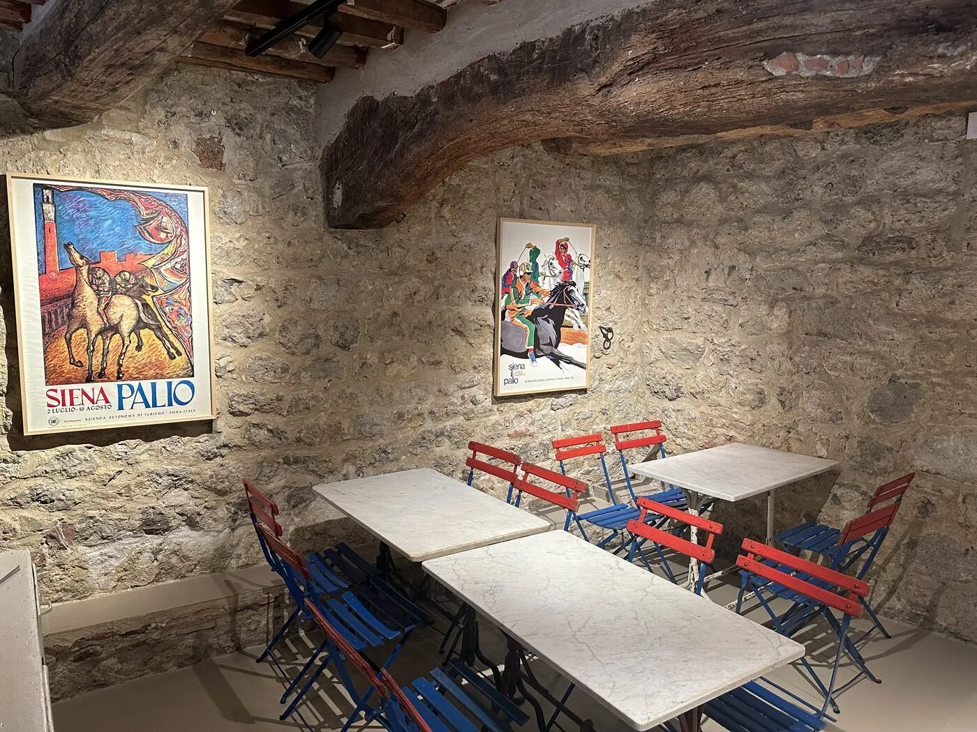La sala interna, con muri in pietra, travi e manifesti del Palio