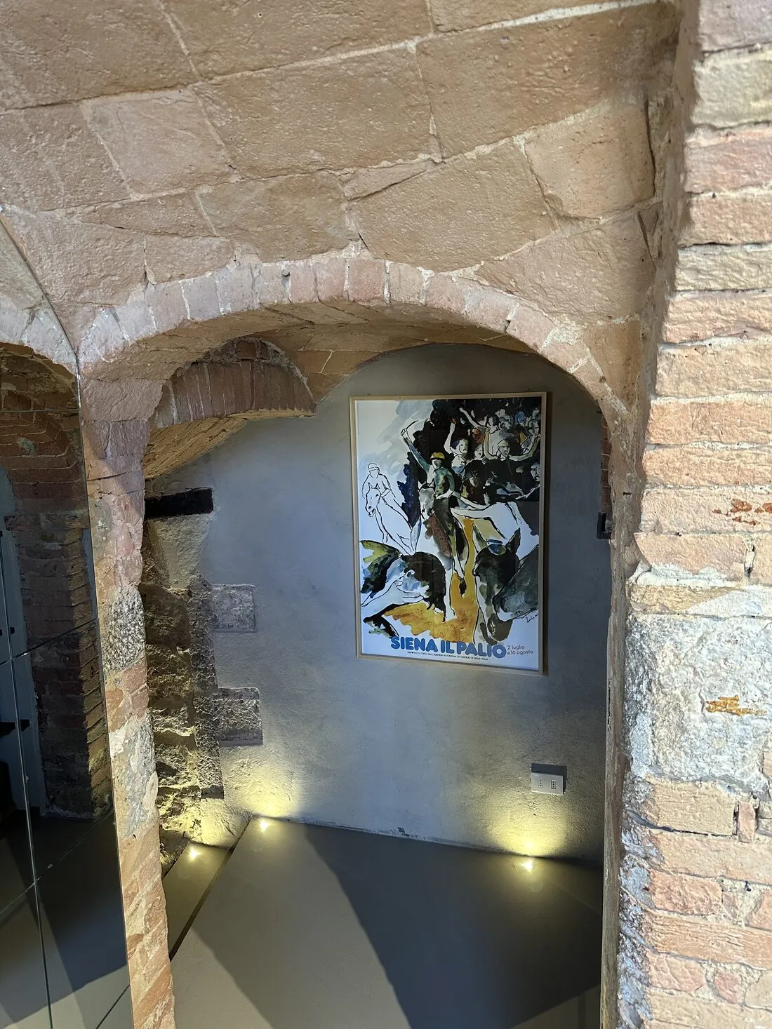 L'arco in pietra della sala con il manifesto del Palio